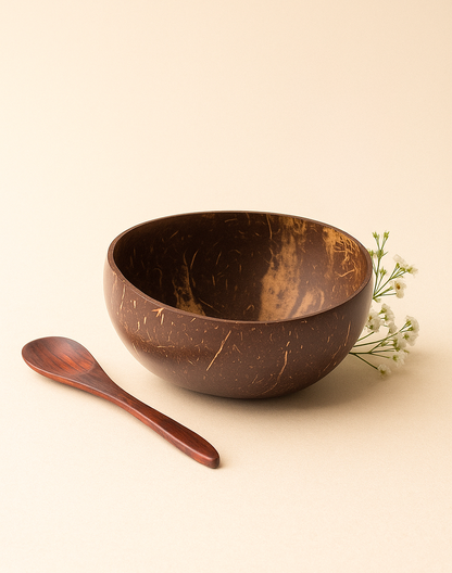 Bol en noix de coco naturel brun accompagné d'une cuillère en bois et de petites fleurs blanches