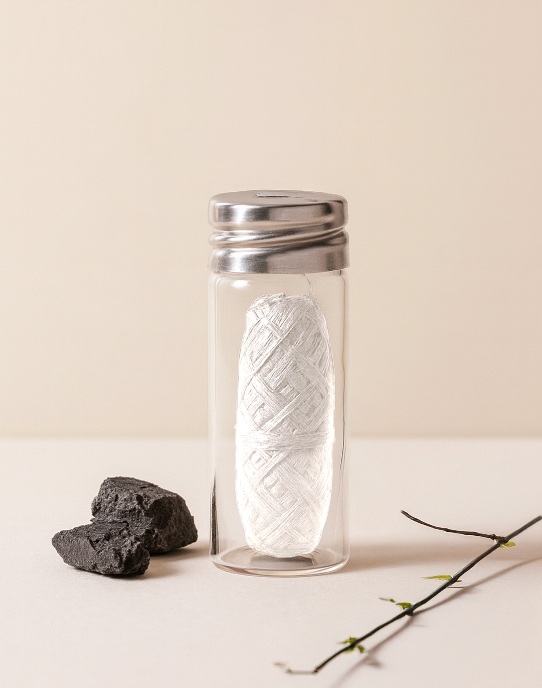 Fil dentaire blanc en fibre de bambou dans un flacon en verre à bouchon métallique, morceaux de charbon